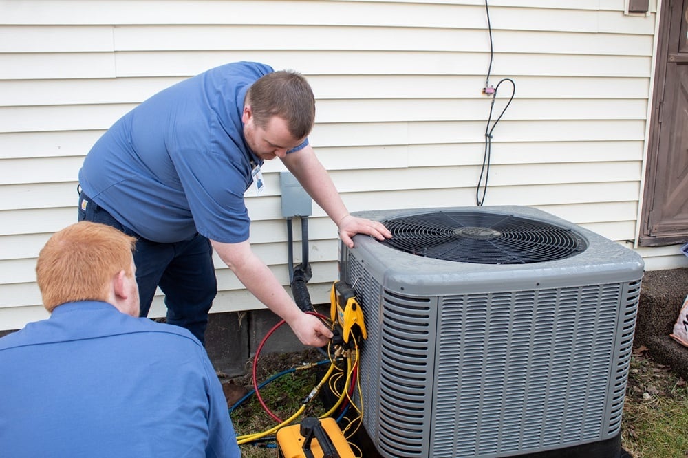 Two Honest Fix HVAC technicians diagnosing an outdoor air conditioner condenser unit during an AC service call