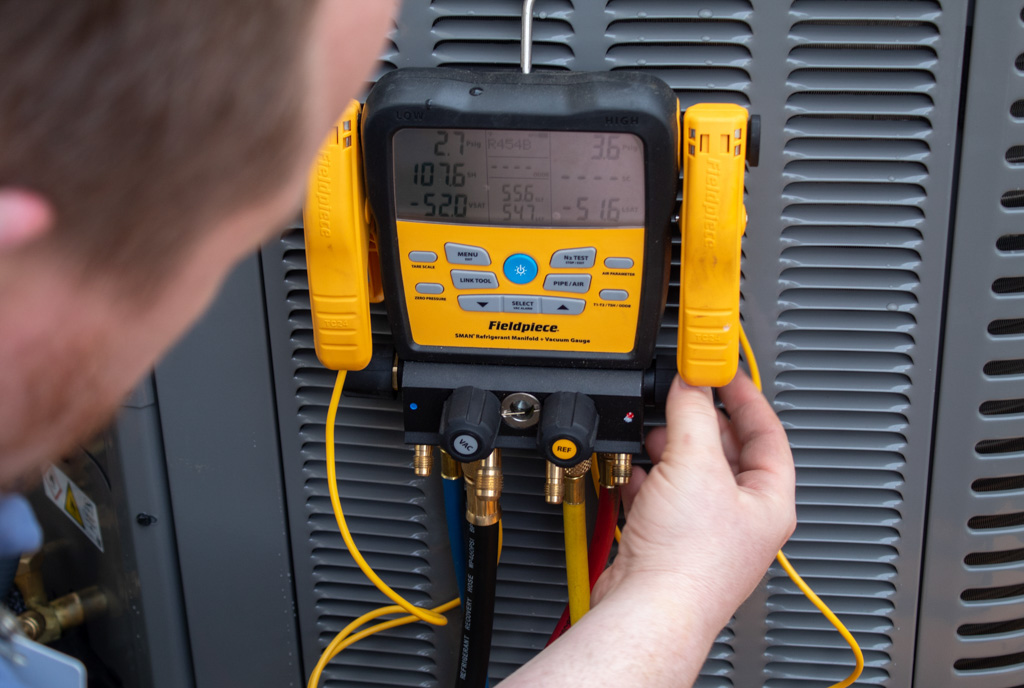 Honest Fix technician checking refrigerant pressure with digital gauges during AC diagnostic service in Steubenville, Ohio.