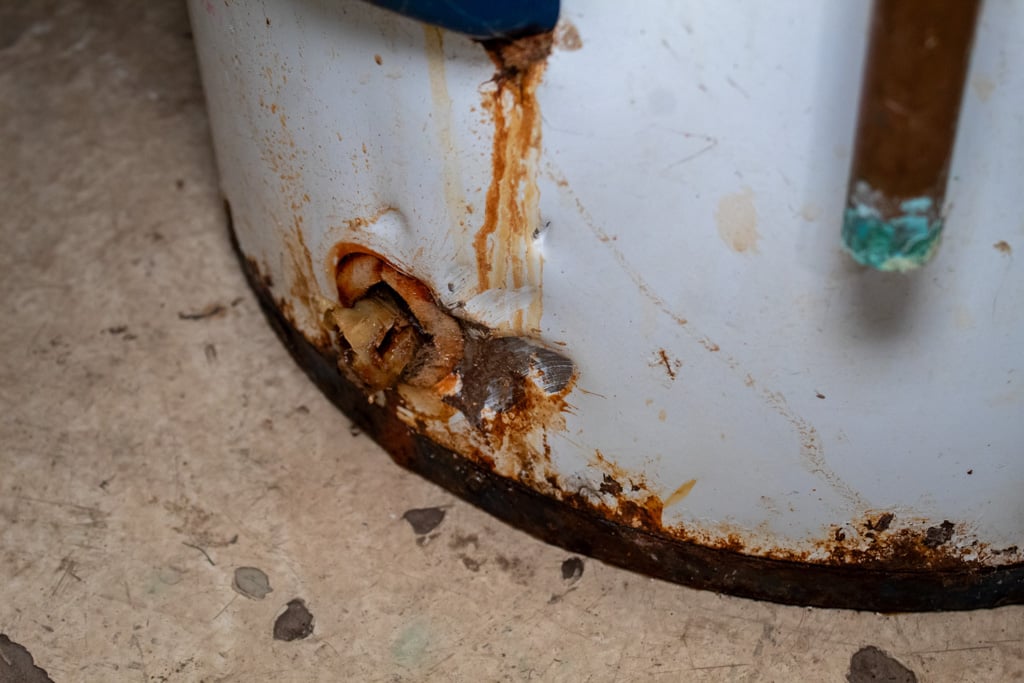 Close-up of rust and leakage damage at the bottom of a residential water heater tank in Steubenville, Ohio.