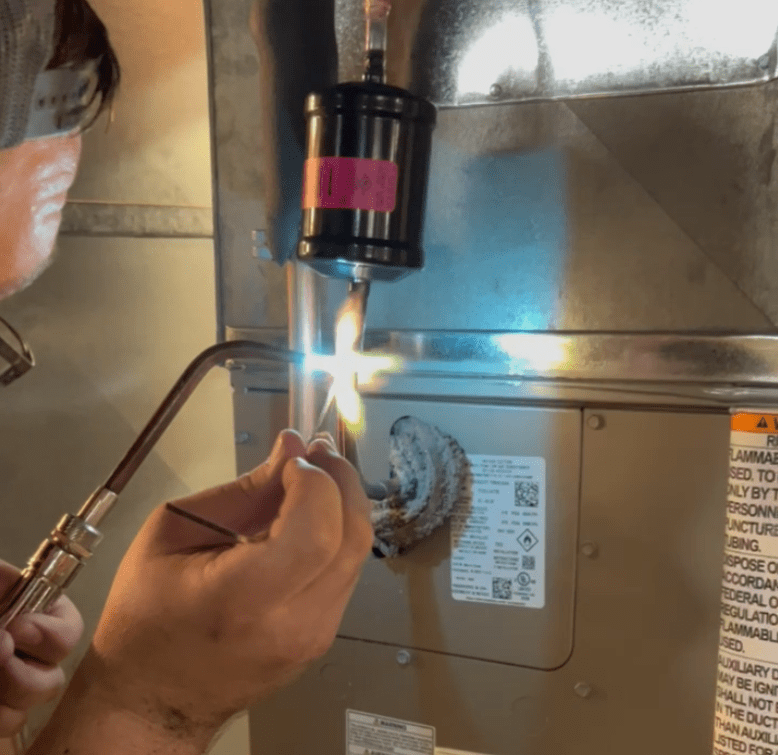 Honest Fix technician brazing refrigerant line to a air handler.