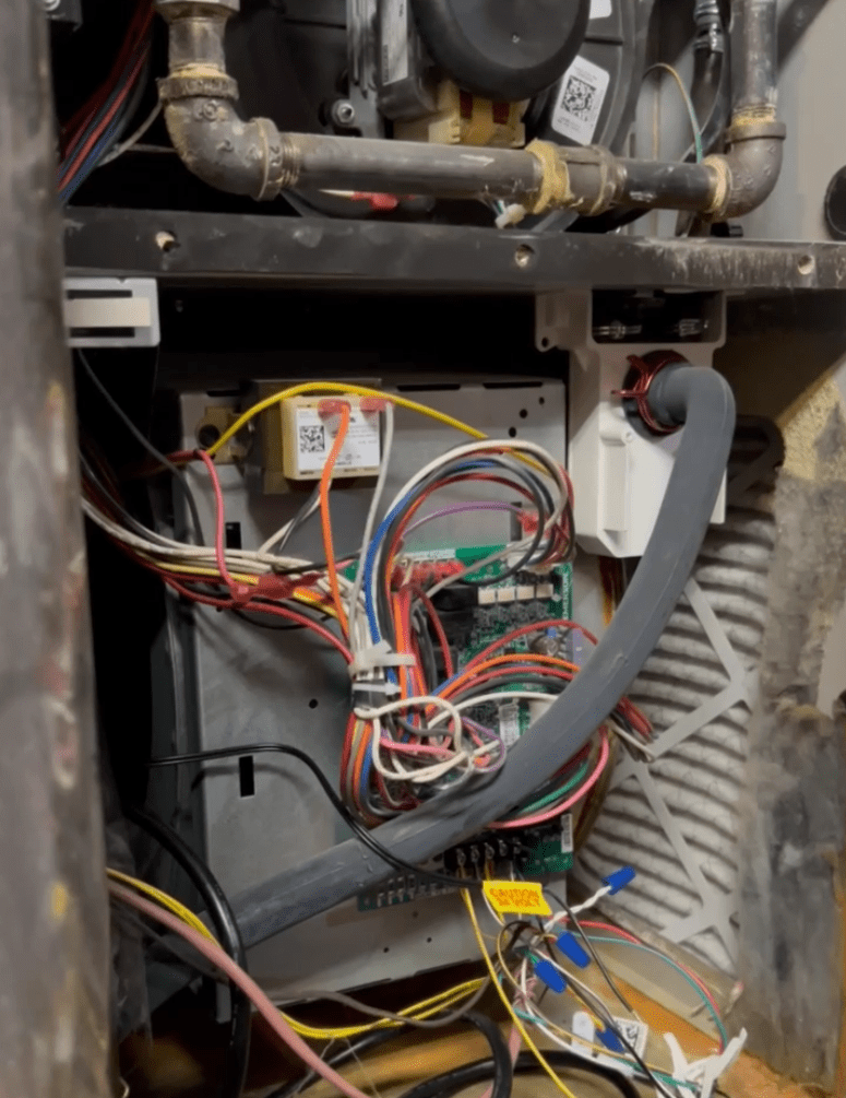 Honest Fix Heating, Cooling & Plumbing technician inspecting and repairing furnace circuit board wiring inside a gas furnace in Steubenville, OH.