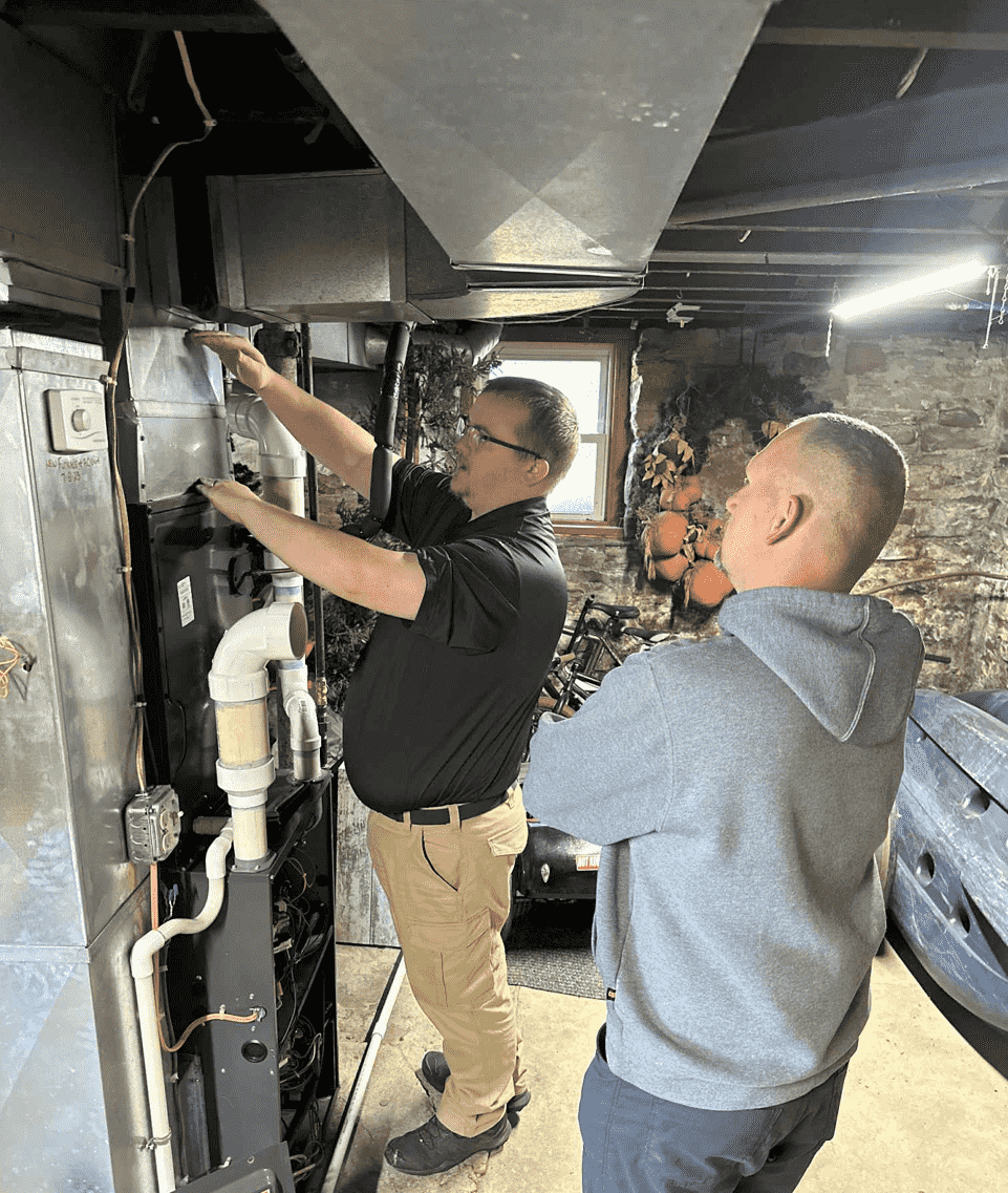 Owner Alex Largent of Honest Fix Heating, Cooling & Plumbing inspecting a furnace system with a homeowner in Steubenville, OH.